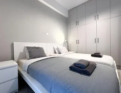 a white bedroom with two beds and white cabinets at Eva's House - 2 Bedroom Apartment in Athens