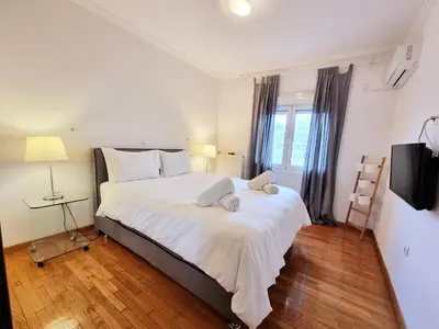 a bedroom with a large bed with white sheets at In the Heart of the Center in Athens