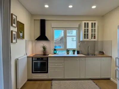 a kitchen with white cabinets and a window at Martino apartment in Athens