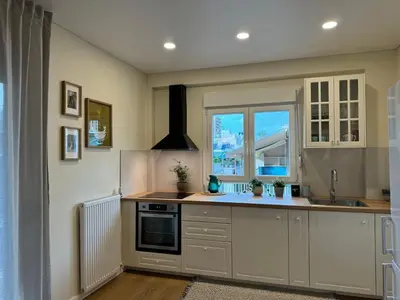 a kitchen with white cabinets and a sink and a window at Martino apartment in Athens