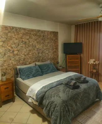 a bedroom with a large bed with a stone wall at Home4U apt2, just 8Km from airport in Markopoulo