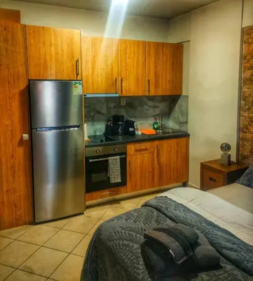 a kitchen with a stainless steel refrigerator and wooden cabinets at Home4U apt2, just 8Km from airport in Markopoulo