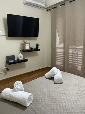 a bedroom with towels on a bed with a flat screen tv at Modern Studio in Palaio Faliro in Athens
