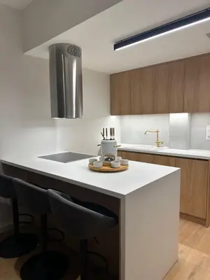 a kitchen with a white island with bar stools at YPSILON Apartment in Athens