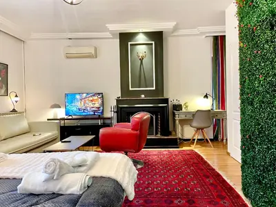 a living room with a bed and a red chair at Konstantinia comfort studio in Athens