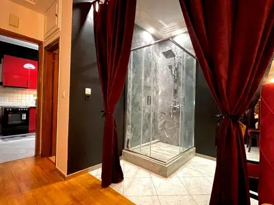a glass shower in a room with red curtains at Konstantinia comfort studio in Athens