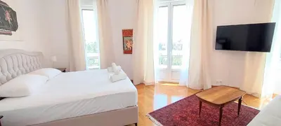 a bedroom with a white bed and a flat screen tv at Grand suite in the temple of Zeus in Athens