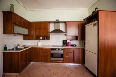 a kitchen with wooden cabinets and a stainless steel refrigerator at Μεγάλο Διαμέρισμα με ευρύχωρο μπαλκόνι στην Αθήνα in Athens