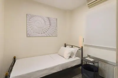 a small room with a white bed and a chair at Spacious 3bdr Apartment with Monumental View in Athens