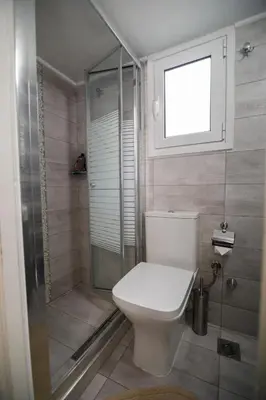 a bathroom with a toilet and a shower with a window at Bright small penthouse in the center of athens in Athens