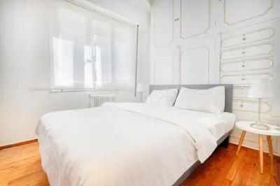 a white bedroom with a white bed and a window at Syntagma Apartment in Athens