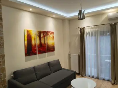 a living room with a couch and a painting on the wall at Luxury stay near the Acropolis 10-min walk to history! in Athens
