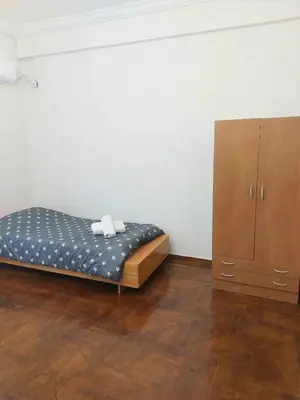 a bedroom with a bed and a wooden cabinet at Dormitory Bunk bed 5' from metro in Athens