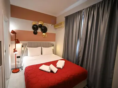 a bedroom with a red bed with two white towels at Iris suite Stadiou by Zeussuites in Athens