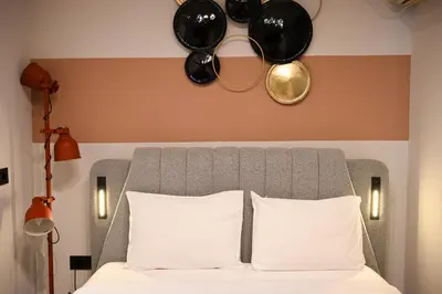 a bed with white pillows and plates on the wall at Iris suite Stadiou by Zeussuites in Athens