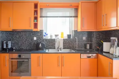 an orange kitchen with a sink and a window at Designers apartment in Galatsi area in Athens