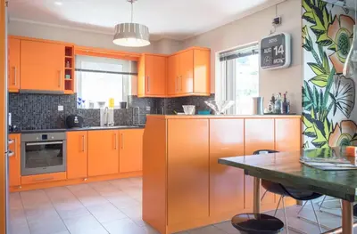 a kitchen with orange cabinets and a table at Designers apartment in Galatsi area in Athens