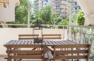 a wooden table with two chairs and a lamp on a balcony at Designers apartment in Galatsi area in Athens