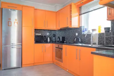a kitchen with orange cabinets and a stainless steel refrigerator at Designers apartment in Galatsi area in Athens