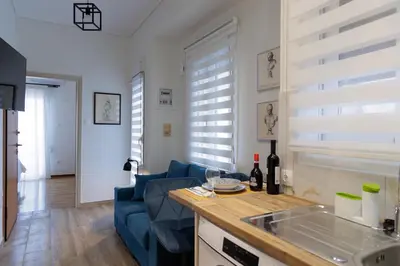 a kitchen and living room with a blue couch at Thea Luxury Rooms Athens in Athens