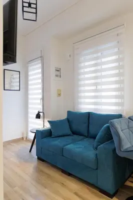 a blue couch in a living room with a window at Thea Luxury Rooms Athens in Athens
