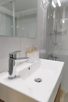 a white bathroom with a sink and a shower at Thea Luxury Rooms Athens in Athens