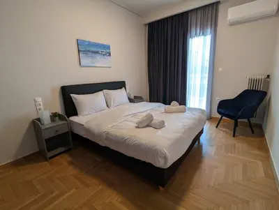a bedroom with a bed with a chair and a window at Spacious seaside flat at alimos in Athens