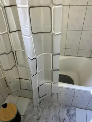 a bathroom with a tub and white tile walls at Atelier Ioulianou 72 in Athens