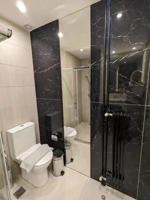a bathroom with a toilet and a glass shower at Spacious and sunlit seaside flat in Athens
