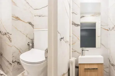 a white bathroom with a toilet and a sink at Spacious and sunlit seaside flat in Athens
