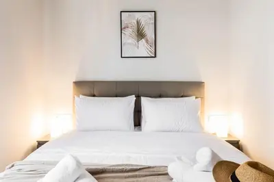 a bedroom with a large white bed with two lamps at Spacious and sunlit seaside flat in Athens