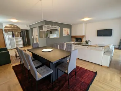 a dining room and living room with a table and chairs at Spacious and sunlit seaside flat in Athens