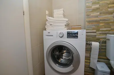 a white washing machine in a bathroom with towels at Vouliagmeni Bay Stylish house with private garden in Athens