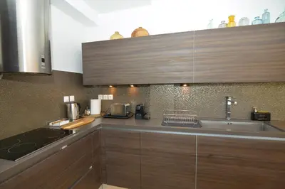 a kitchen with wooden cabinets and a sink at Vouliagmeni Bay Stylish house with private garden in Athens