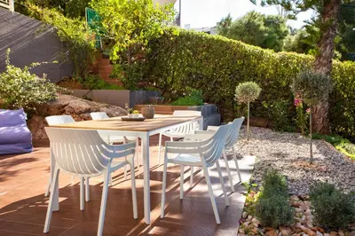 a wooden table and chairs in a garden at Vouliagmeni Bay Stylish house with private garden in Athens