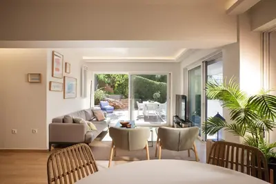 a living room with a couch and a table and chairs at Vouliagmeni Bay Stylish house with private garden in Athens