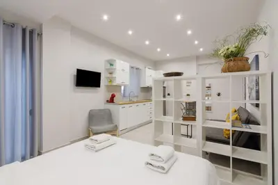 a white room with a bed and a kitchen at A little gem in the heart of Athens in Athens