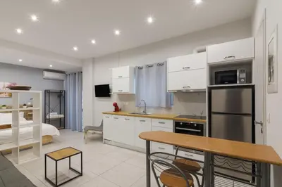 a kitchen with white cabinets and a bed in a room at A little gem in the heart of Athens in Athens