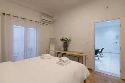 a white bedroom with a bed and a vase of flowers at Heaven apartment in the heart of Athens in Athens