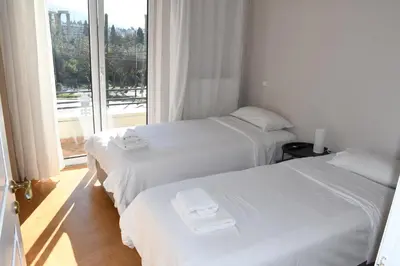 two white beds in a room with a window at Adrianos Gate View Apartment in Athens