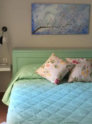 a bed with two pillows and a painting on the wall at Casa Arsida in Anavissos