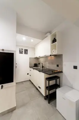 a kitchen with white cabinets and a television at Athenian Kolonaki Apartment in Athens