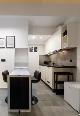 a kitchen with white cabinets and a table with a computer at Athenian Kolonaki Apartment in Athens