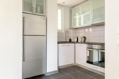 a kitchen with white cabinets and a refrigerator at Eclipse Vouliagmeni Center in Athens