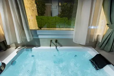a jacuzzi tub in a room with a window at The Athenian Aroma - Suite with Jacuzzi in Athens
