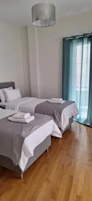 two beds in a room with wooden floors at Xenia's Elegant Acropolis Suite in Athens