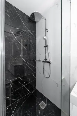 a bathroom with a shower with black tiles at Spacious & Stylish Athens Apartment - Walk to Metro in Athens
