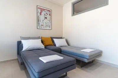 a living room with a couch and a ottoman at Charming minimal apt in the center of Glyfada in Athens
