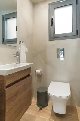 a bathroom with a toilet and a sink and a window at Charming minimal apt in the center of Glyfada in Athens