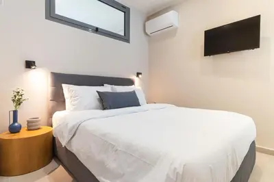 a bedroom with a bed and a tv on the wall at Charming minimal apt in the center of Glyfada in Athens